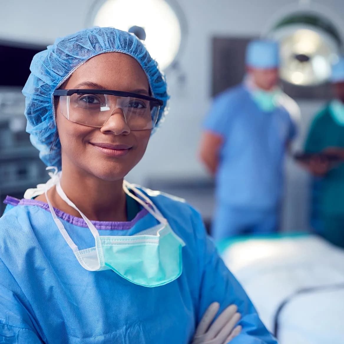 Woman standing and smiling in scrubs with the arms crossed